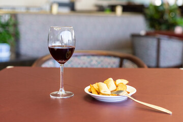 wineglass, potato wedges, spring rolls on a dark-red table