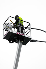 a repairman in overalls on a tower repairing a road lamp. Electrical repair man at work fixing a street light.