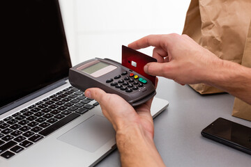 Male hands with credit card into card machine or pos terminal isolated on white background