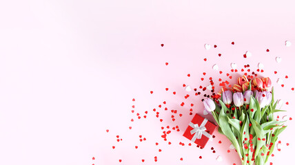 Obraz na płótnie Canvas Pink tulips with decorative heart sprinkles on soft pastel light background. Top view. Valentines day festive background.