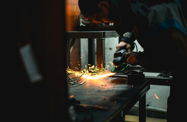 Locksmith using angle grinder in unlit workshop 