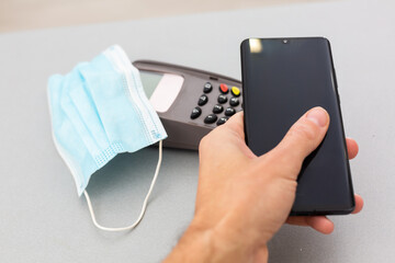 Modern consumer keeping smartphone over cashier-machine to pay for purchase,