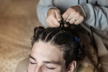 The teenage boy wanted to change something in his appearance and asked his mother to braid him pigtails, now the guy has a modern hairstyle