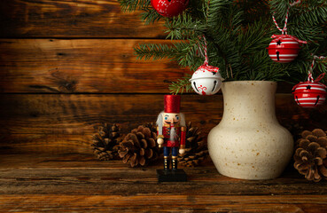 Christmas nutcracker wooden figure, cones and handmade ceramic flower vase with Christmas tree branches and decorative sleigh bells pendant ornaments. Beautiful, festive toy soldier with copyspace.