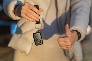 Woman holding key of her new car. Woman has got driving license and ready to drive