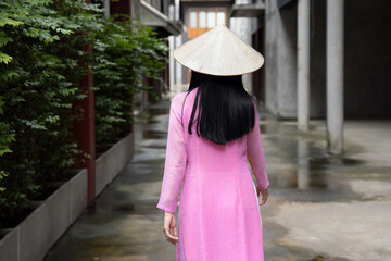 Back of random anonymous Vietnamese woman in southeast asian travel scene, portrait of exotic asian Vietnam woman in traditional Vietnamese Ao Dai dress with Vietnamese stylized hat