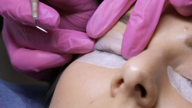 Modern eyelash lamination procedure in a professional beauty salon. The master applies special silicone curlers before the eyelash curling procedure.