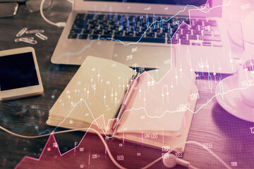 Multi exposure of financial graph drawings and desk with open notebook background. Concept of forex