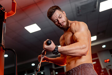 Fototapeta na wymiar Handsome brunette fitness man trains in a gym on a sport equipment. Trainings for better results.