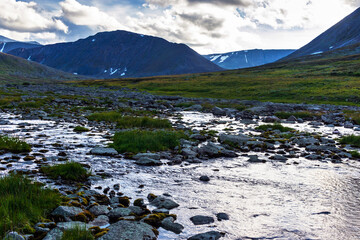 cold stream and mountain range on a summer evening