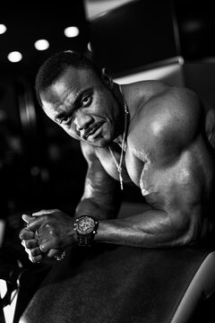 Sport portrait of african american athlet. Strong bodybuilder man posing in gym. Black and white portrait.