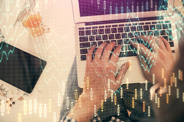 Double exposure of man's hands typing over laptop keyboard and forex chart hologram drawing. Top view. Financial markets concept.