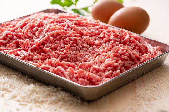 Minced meat and eggs in a tray on a wooden background