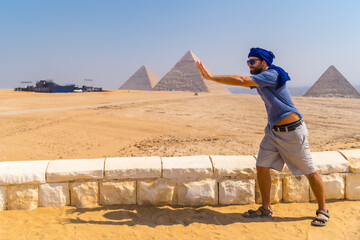 A young tourist joking at The Pyramids of Giza, the oldest Funerary monument in the world. In the...
