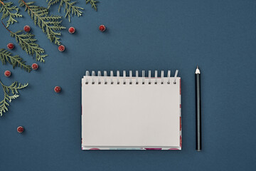 New Year's decor and a notebook in the center on a blue background. Christmas decoration. Copy space, flat lay, mock up, top view.