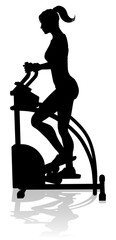 A woman in silhouette using an elliptical cross fit gym equipment exercise machine