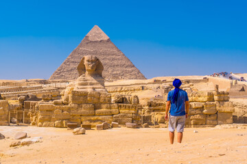 Fototapeta na wymiar A young man walking towards the Great Sphinx of Giza and in the background the pyramid of Khafre, the pyramids of Giza. Cairo, Egypt