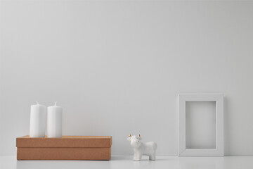 Fototapeta na wymiar Porcelain figurine of a bull and New Year's decor and candles. Copy space, mock up.