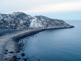 Amazing black pebble beach of Barents Sea coast near Teriberka. Winter on Kola Peninsula, Murmansk Oblast, Russia