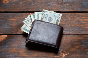Male wallet with dollars. Purse with dollar bills on a wooden background.