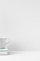 The mug stands on a stack of books on a white background. Natural and eco-friendly materials. Copy space, mock up.