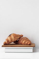 Croissants on a wooden board on a white background. Natural and eco-friendly materials. Copy space, mock up