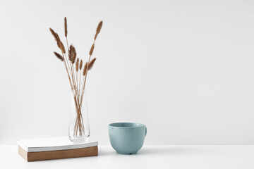Mug and transparent vase with flowers on a white background. Eco-friendly materials in the decor of the room, minimalism. Copy space, mock up.