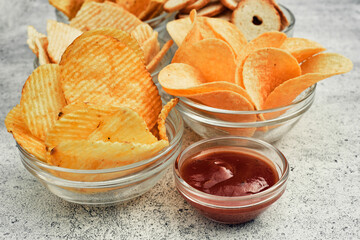 Potato and corn chips, snacks, crackers in transparent glass plates and sauces. Mix of snacks.