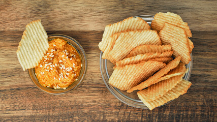 Fluted potato chips on a wooden board with sauce. Snack, ready meal menu, junk food. Close up.