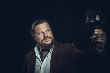 Stylish bearded man dressed in brown jacket with glass of whisky