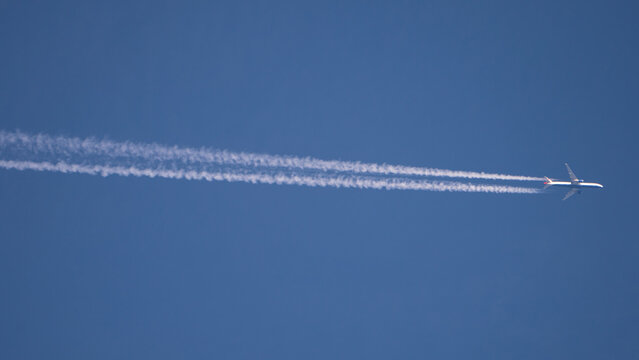 Passagierflugzeug mit Kondensstreifen am blauem Himmel