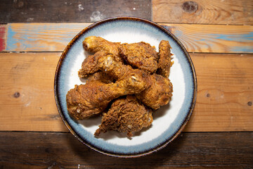 A plate of crispy fried chicken legs on a wooden kitchen work top