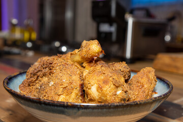 A plate of crispy fried chicken legs on a wooden kitchen work top