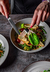 woman eating healthy salad from bowl sitting in cafe