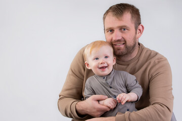 On a gray background, a portrait of a father and a little one-year-old smiling son.