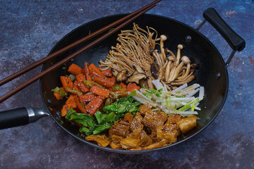 Vegan stir fry in black wok on gray background, copy space