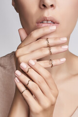 Cropped portrait of lady with golden rings on fingers. Jewelry set consists of six rings: two rings...