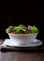 Salad with cherry Tomatoes, Cucumber,  Lettuce and Kalamata Olives on dark wooden Background. 