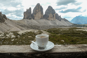 A cup of coffee with the view on the famous Tre Cime di Lavaredo (Drei Zinnen) in Italian Dolomites. The mountains are surrounded by thick clouds. Enjoying the moment. Relaxation and chill.
