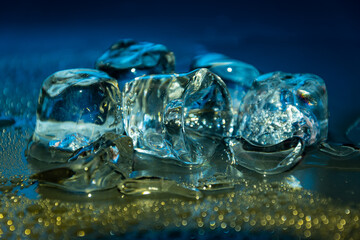 Melting frozen ice cubes illuminated with gradient coloured LED light in the dark.