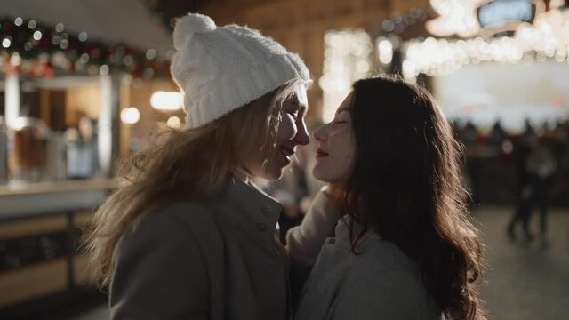 Portrait of sensual moment between two female friends, celebrating christmas outside together. Girls almost kiss, being very close, sharing magnifficent time.