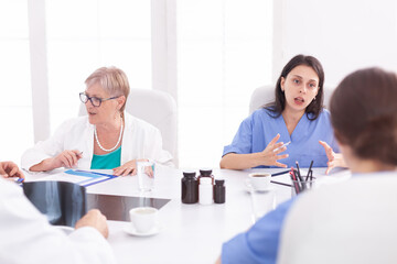 Medical team sitting and discussing about patient diagnosis in conference room. Clinic expert therapist talking with colleagues about disease, medicine professional