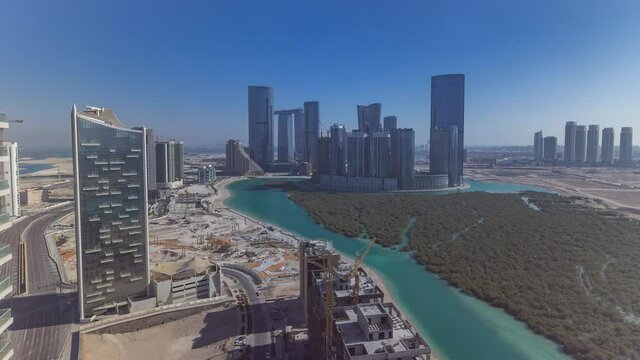 Buildings on Al Reem island in Abu Dhabi all day timelapse from above. Aerial citiscape of Al Reem Island, showing the reflection of buildings in the water and long shadows mooving fast.
