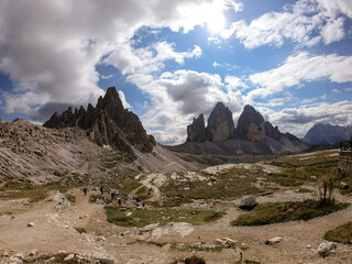 Fototapeta premium Panoramic view on a valley in Dolomites, Italy. There are sharp and steep mountain slopes around. Lots of lose stones and pebbles. The sky is full of soft clouds. Raw landscape. Serenity and calmness