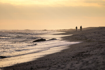 Silhouette of people walking along the beach during sunset. Long Island New York