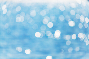 Delicate blue texture bokeh sea. Summer background. Blurry blue bokeh glare on the water on a sunny day. Concept travel.