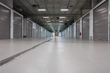 Obraz premium Large Storage warehouse corridor interior. Metal garage doors with locks. Low angle shot