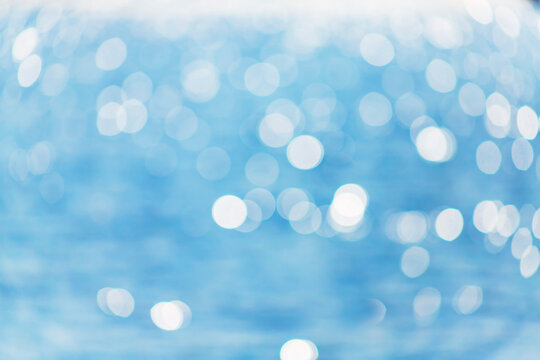 Delicate blue texture bokeh sea. Summer background. Blurry blue bokeh glare on the water on a sunny day. Concept travel.