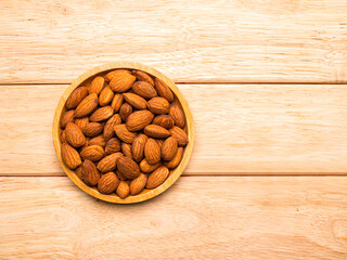 Top view almonds in wood plate on pine wood table with copy space.