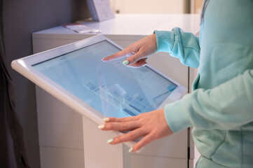 Faceless woman touching the screen of a self-service device in a store. Device store navigator....